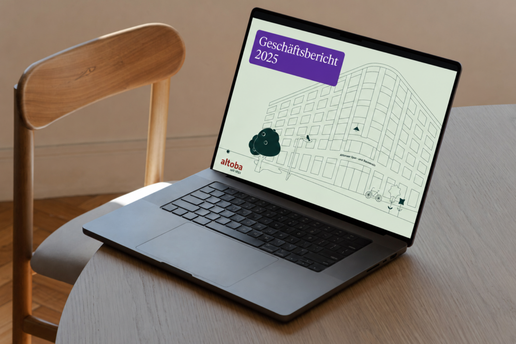 Geöffneter Laptop auf einem Tisch mit der Titelseite des altoba-Geschäftsberichts 2025 auf dem Bildschirm, die eine stilisierte Gebäudezeichnung und das altoba-Logo zeigt.
