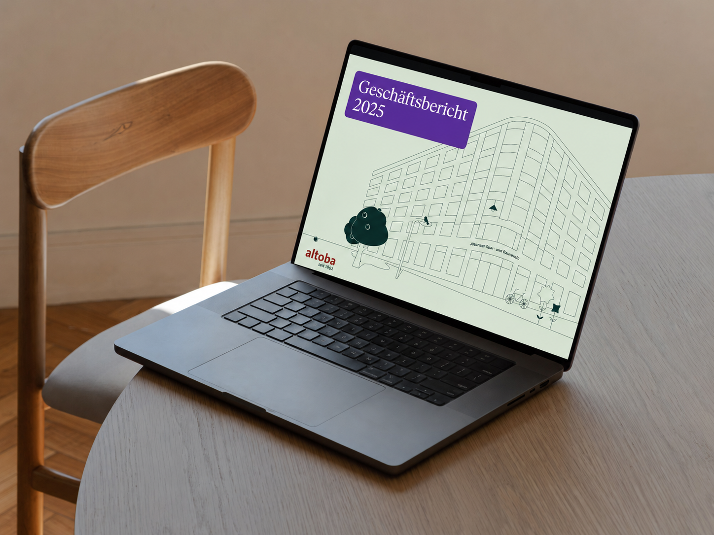 Geöffneter Laptop auf einem Tisch mit der Titelseite des altoba-Geschäftsberichts 2025 auf dem Bildschirm, die eine stilisierte Gebäudezeichnung und das altoba-Logo zeigt.